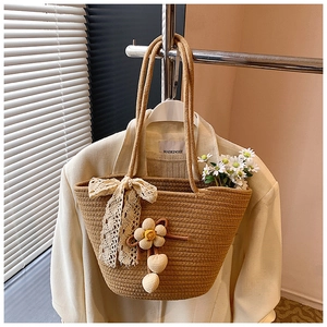 Detail of woven straw bucket bag featuring lace bows and handmade floral charms