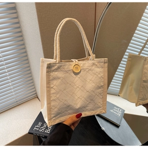 Dettaglio borsa pranzo in tela bianca con bottone giallo e manico in corda intrecciata