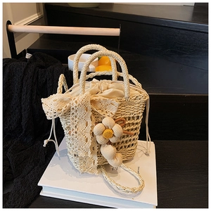 Detail of hand-woven straw bag with lace bow, floral charm, and drawstring lining