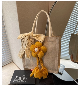 Dettaglio borsa in juta con fiocco di pizzo e ciondolo a forma di fiore giallo
