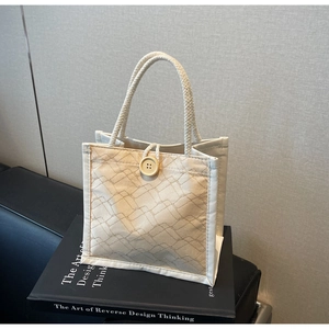 Dettaglio della borsa da pranzo trapuntata beige con manici in corda e bottone in legno