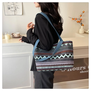 Ethnic style tote bag with geometric patterns and blue woven straps in use