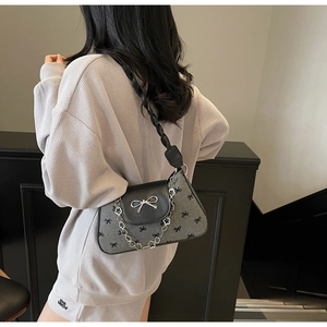 Detail of grey bow-patterned bag featuring a metal bow buckle and floral chain strap