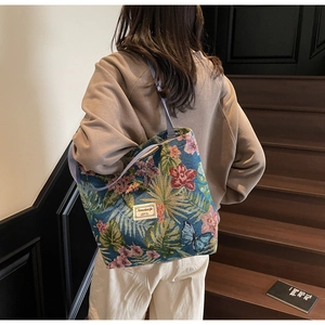Detail of vintage floral canvas tote bag with butterfly patterns and purple woven handles