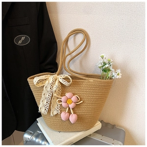 Detail of handmade straw bucket bag with lace bow and crochet floral cherry pendant