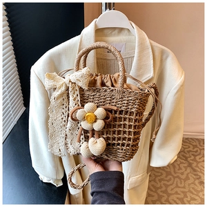 Detail of straw woven basket bag with white lace bow and floral charm accessory