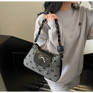 Detail of grey bow-pattern crossbody bag with metal floral chain and woven leather handle