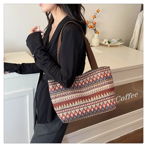 Ethnic tote bag with geometric patterns shown on shoulder in a cozy cafe setting