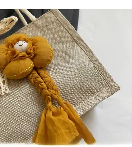 Dettaglio di un ciondolo floreale giallo fatto a mano su una borsa in lino