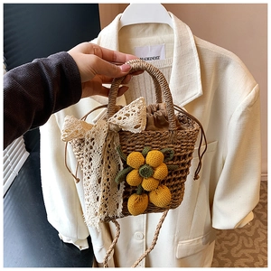Detail of handmade straw bucket bag featuring yellow crochet fruits and lace bow decoration