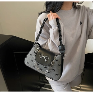 Detail of grey wool shoulder bag with black bow patterns and silver flower chain strap