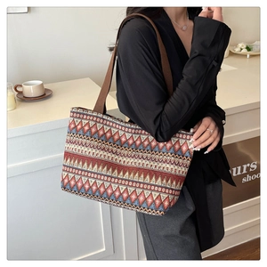 Detail of ethnic geometric wave pattern and brown woven strap on a vintage tote bag