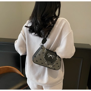 Close-up of the grey fabric bow pattern and silver metal floral chain on the handbag