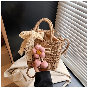 Detail of woven straw tote bag with pink crochet flowers and beige lace ribbon