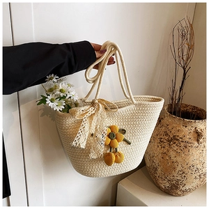 Detail of cream woven tote bag featuring handmade crochet flowers and lace bow accents