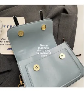 Detailed view of light blue leather bag featuring dual gold magnetic closures and neat stitching