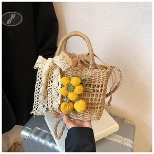 Close-up of handmade straw bag with crochet flowers, cherries and lace bow detail