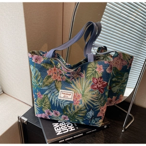 Detailed texture of blue jacquard tote bag with pink flowers and palm leaf embroidery