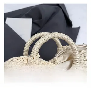 Détail des poignées tissées rondes et du nœud en dentelle sur un sac seau en paille