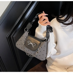 Detail view of heart pattern bag with silver bow buckle and decorative metal floral chain