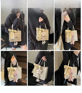 Dettaglio borsa da pranzo in lino beige con fiocco in pizzo e ciondolo a nappa floreale