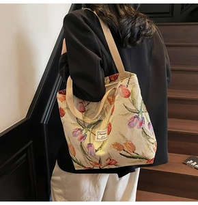 Detail of off-white woven tote bag with colorful tulip print shown on shoulder