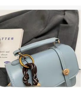 Detail of light blue leather handbag with golden metal rings and woven strap ornament