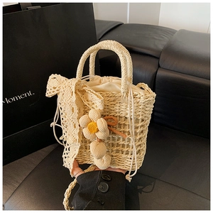 Detail of hand-woven beige tote with delicate lace bow and crochet flower pendant
