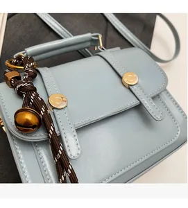 Close-up of light blue PU leather handbag showing fine texture and golden metal buckle