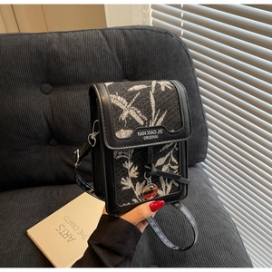 Detail of vintage crossbody bag featuring black leather and bamboo leaf pattern fabric
