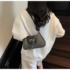 Detail of grey crossbody bag with silver bow ornament and metallic petal chain link