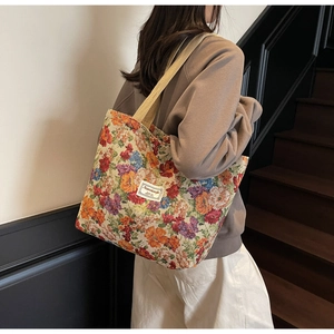 Détail du motif floral coloré sur un grand sac cabas en toile avec bandoulière tissée
