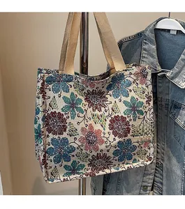 Detailed close-up of floral embroidery texture and woven handles on a tote bag