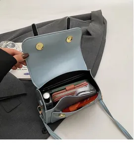Detail view of the spacious inner compartment and gold magnetic clasp of the light blue bag
