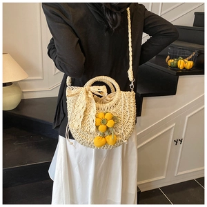 Détail du sac en paille avec nœud en dentelle et fleur tressée pour les vacances
