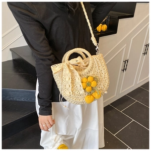 Détail du sac seau en paille tissé main avec nœud en dentelle et fleur au crochet
