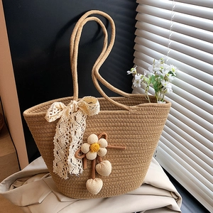 Brown woven straw tote bag with cream lace bows and floral charms for summer beach style