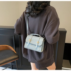 Close-up of light blue small square bag featuring golden buckle details and sleek PU leather