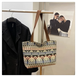 Detail view of ethnic canvas tote bag with geometric patterns hanging on a metal rack