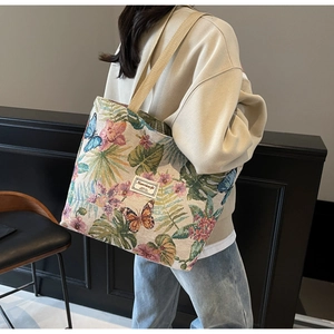 Detail of large canvas tote bag with colorful floral jacquard and brand logo patch