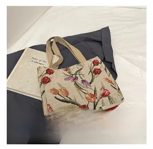 Dettaglio della borsa tote in jacquard intrecciato con motivi di tulipani e manici beige