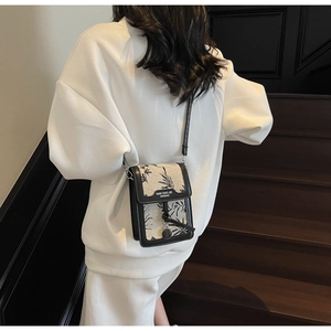 Detail of jacquard crossbody bag with floral patterns and black leather trim accents