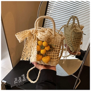 Detail of handmade straw bag with beige lace bow and yellow knit floral charms