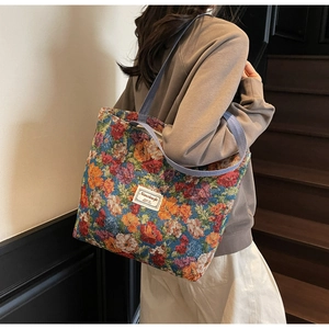 Détail du sac cabas en toile fleurie avec bandoulières bleues et écusson blanc