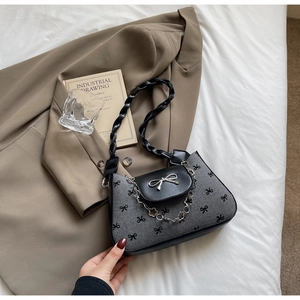 Close-up of gray canvas bag with black bow patterns and silver floral chain strap