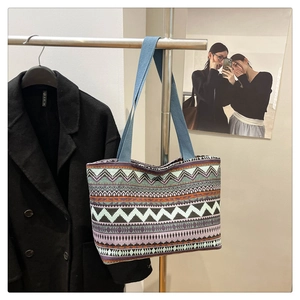 Detail of colorful geometric woven tote bag with blue straps on a display stand