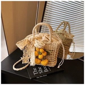 Detailed close-up of handmade woven straw bag with lace bow and yellow knit charm