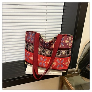 Close-up of ethnic woven tote bag with geometric patterns and red canvas straps