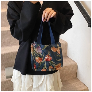 Dettaglio della borsa tote in maglia con tulipani arancioni indossata su una scala