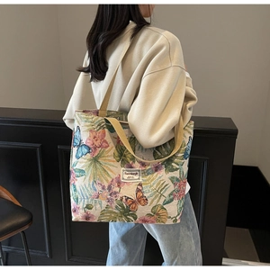 Detail view of large canvas tote bag showing colorful floral and butterfly embroidery